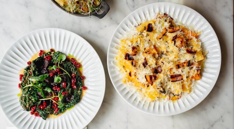 Plates of pasta and salad on a marble table